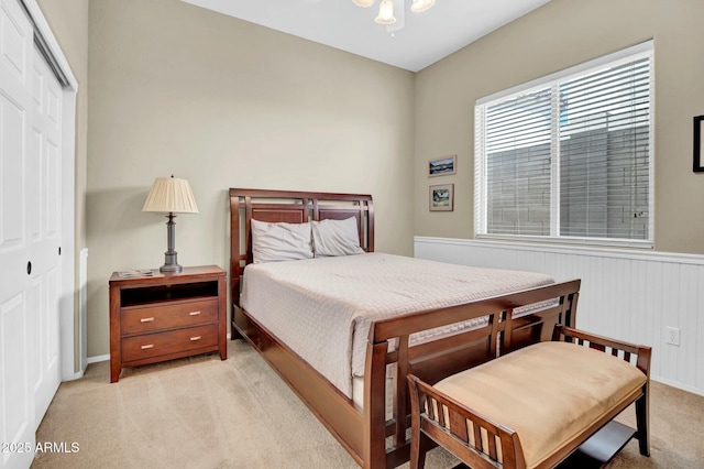 bedroom with a closet, light carpet, and wainscoting