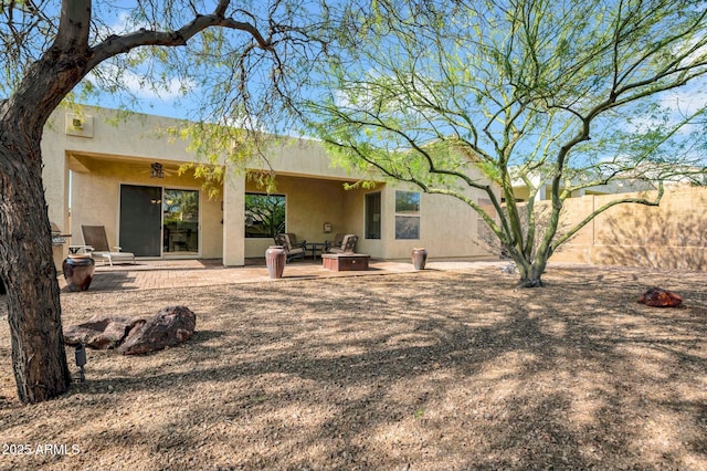 rear view of property featuring a patio area, fence, and stucco siding