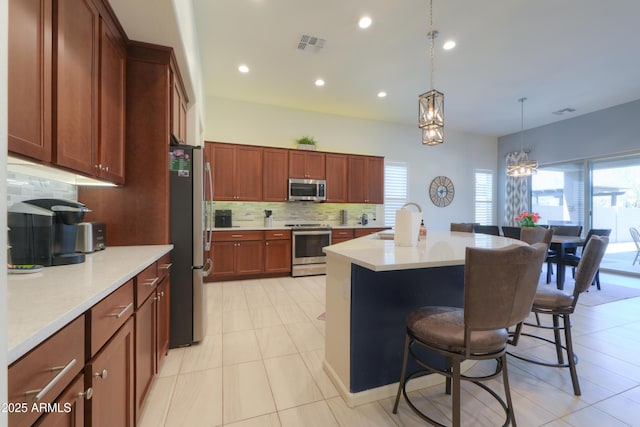 4576 W Agave Ave, Eloy, AZ 85131 - kitchen with a breakfast bar, a center island with sink, stainless steel appliances, light countertops, and visible vents