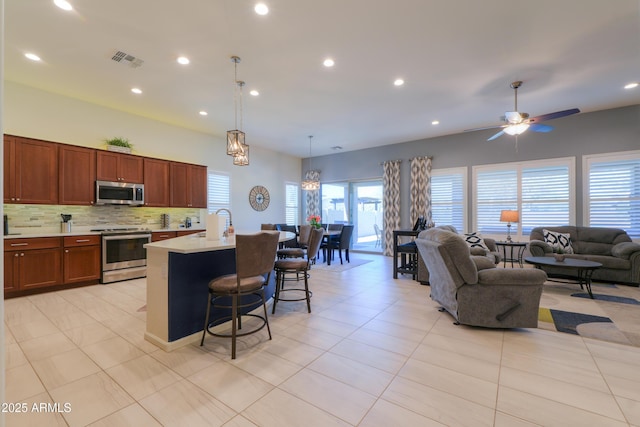4576 W Agave Ave, Eloy, AZ 85131 - kitchen with visible vents, an island with sink, appliances with stainless steel finishes, a breakfast bar, and light countertops