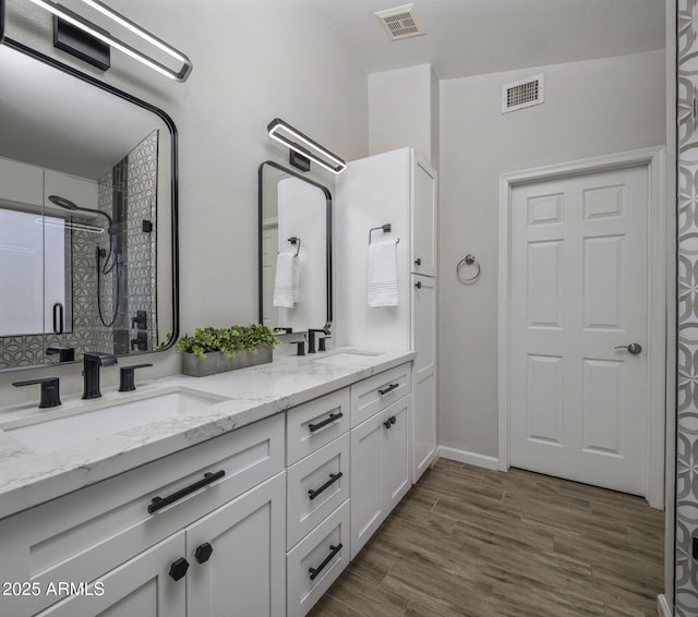 bathroom with hardwood / wood-style flooring, vanity, and a shower