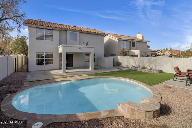 back of property with a fenced in pool, a yard, and a patio