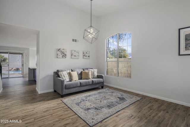 living room with hardwood / wood-style flooring, a chandelier, and a high ceiling