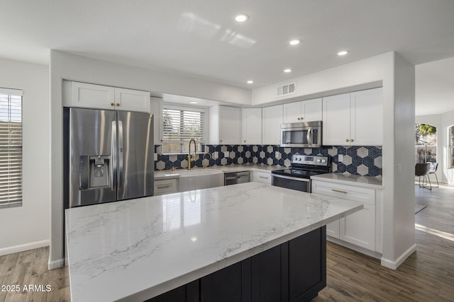 kitchen featuring sink, white cabinets, a center island, light stone counters, and stainless steel appliances