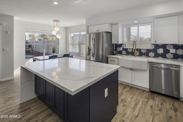 kitchen with pendant lighting, white cabinetry, sink, a center island, and stainless steel appliances