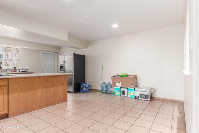 kitchen with light tile patterned floors, recessed lighting, stainless steel fridge, and light countertops