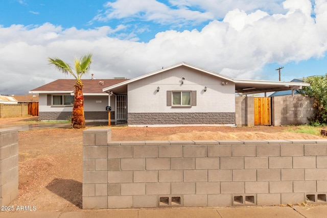 single story home with brick siding, an attached carport, concrete driveway, and fence