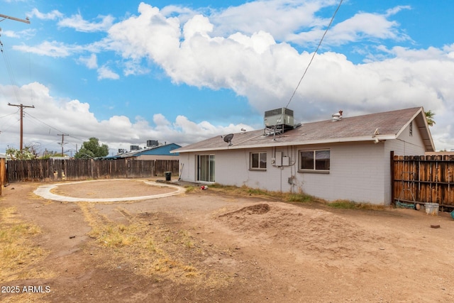 rear view of property featuring central air condition unit and a fenced backyard