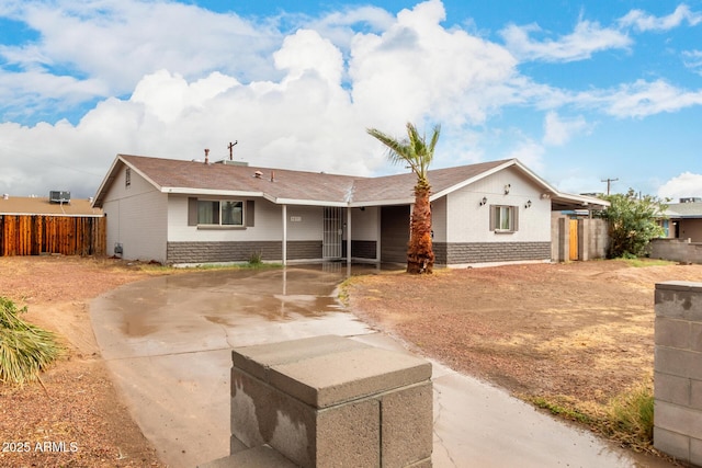 ranch-style house featuring brick siding, concrete driveway, and fence