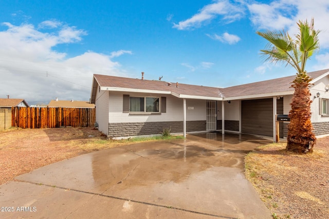 ranch-style home with stone siding, driveway, a garage, and fence