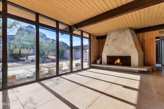 unfurnished living room featuring a mountain view, a large fireplace, wood ceiling, and a wealth of natural light