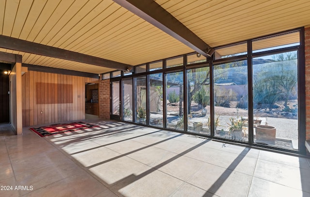 unfurnished sunroom featuring beam ceiling and wood ceiling