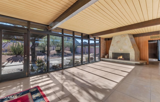 unfurnished sunroom featuring beam ceiling, a large fireplace, and wood ceiling