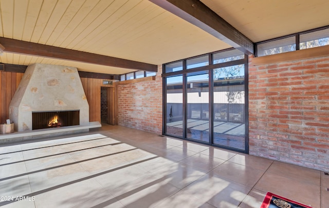 unfurnished living room with beamed ceiling, a large fireplace, tile patterned floors, and floor to ceiling windows