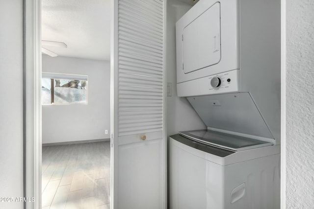 laundry room featuring hardwood / wood-style flooring, ceiling fan, and stacked washer / drying machine