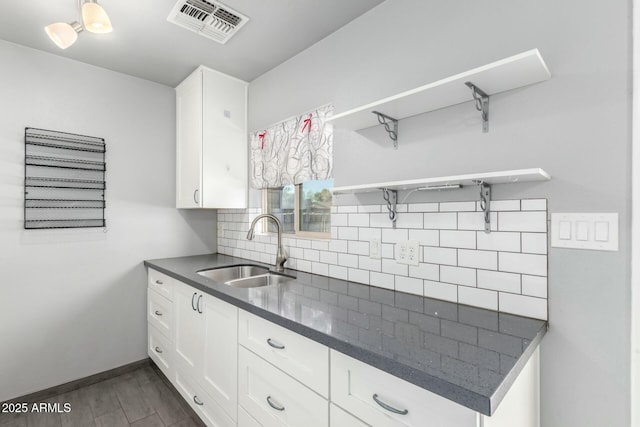 kitchen with white cabinets, backsplash, and sink