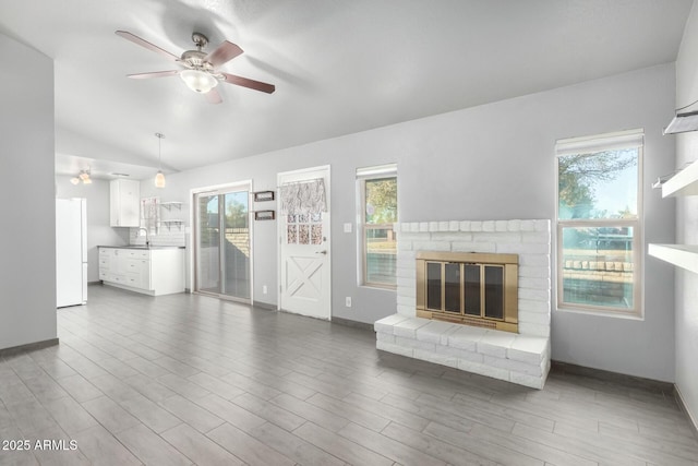 unfurnished living room with plenty of natural light, sink, lofted ceiling, and a fireplace