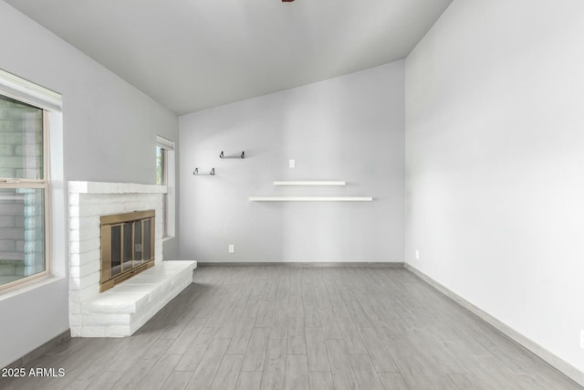 unfurnished living room featuring light hardwood / wood-style floors and a brick fireplace