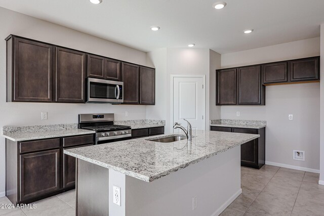 kitchen featuring appliances with stainless steel finishes, dark brown cabinetry, a kitchen island with sink, and sink