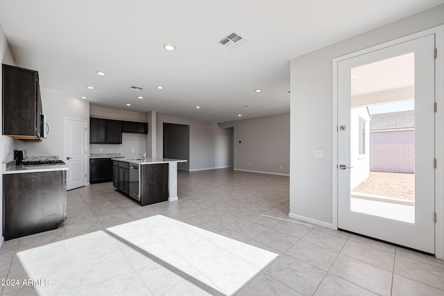 kitchen featuring sink, light tile patterned floors, and a kitchen island with sink