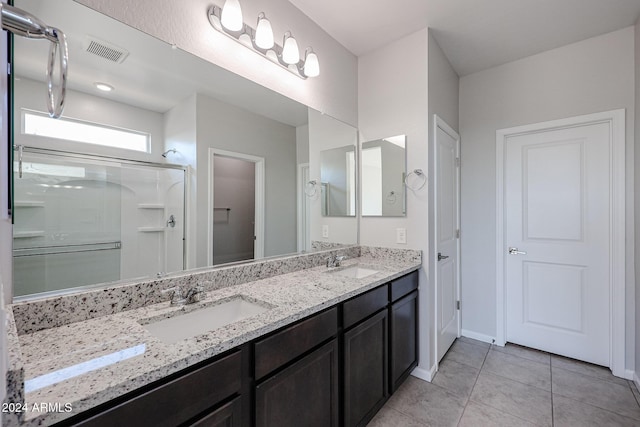 bathroom with tile patterned floors, a shower with door, and vanity