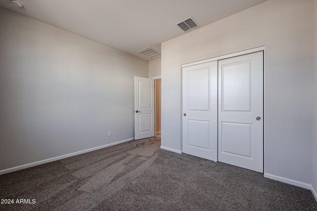 unfurnished bedroom featuring dark colored carpet and a closet