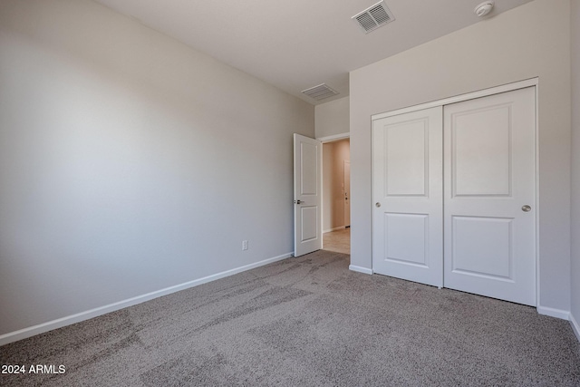 unfurnished bedroom featuring light carpet and a closet