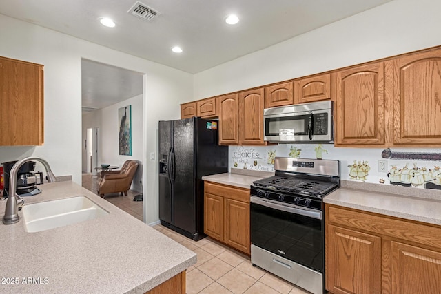 kitchen with appliances with stainless steel finishes, sink, and light tile patterned flooring