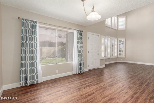 empty room featuring dark wood-style floors, baseboards, and a wealth of natural light