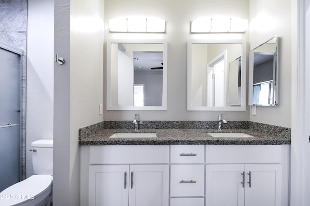 bathroom featuring a shower with door, vanity, and toilet