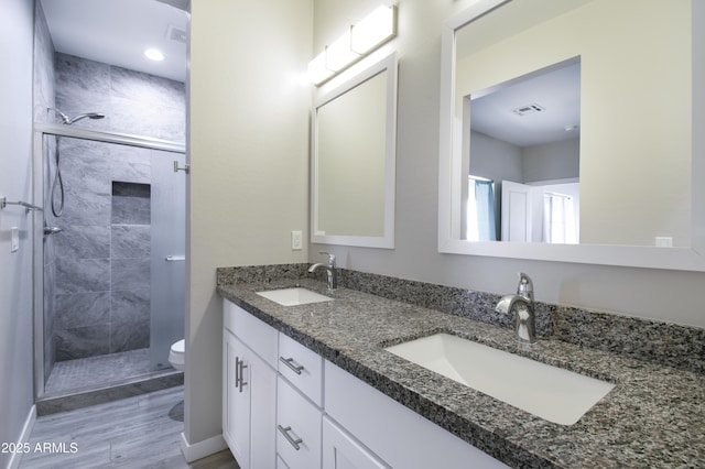 bathroom featuring vanity, a shower with shower door, and toilet