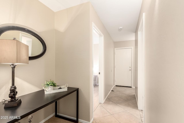 hall featuring light tile patterned floors and baseboards