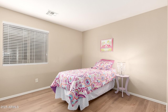 bedroom featuring visible vents, baseboards, and wood finished floors