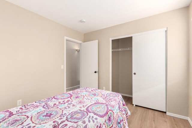 bedroom featuring a closet, light wood-type flooring, and baseboards