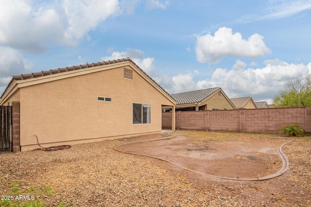 rear view of property with a patio, fence, a tiled roof, and stucco siding