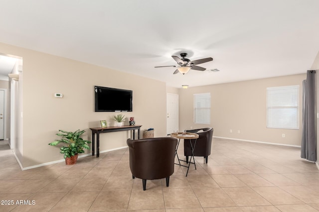 living area featuring light tile patterned floors, ceiling fan, visible vents, and baseboards