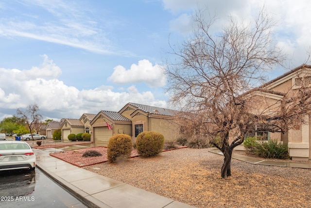 mediterranean / spanish-style house with an attached garage, a tile roof, concrete driveway, and stucco siding