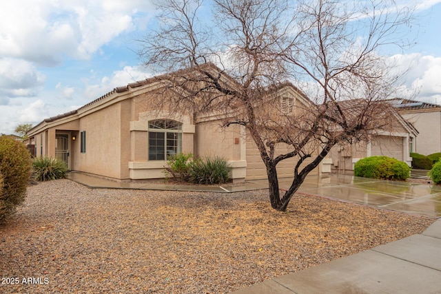 view of front of house featuring a garage, concrete driveway, a tile roof, and stucco siding