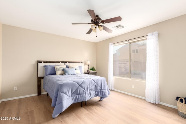 bedroom featuring a ceiling fan, wood finished floors, visible vents, and baseboards