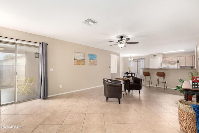 living room with light tile patterned floors, baseboards, visible vents, and ceiling fan with notable chandelier