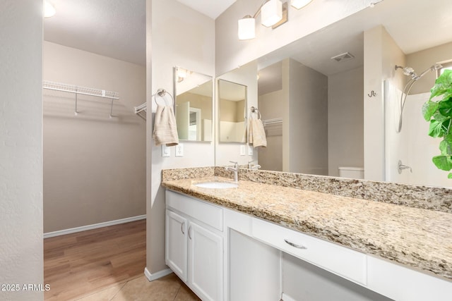 full bathroom featuring visible vents, toilet, vanity, baseboards, and walk in shower