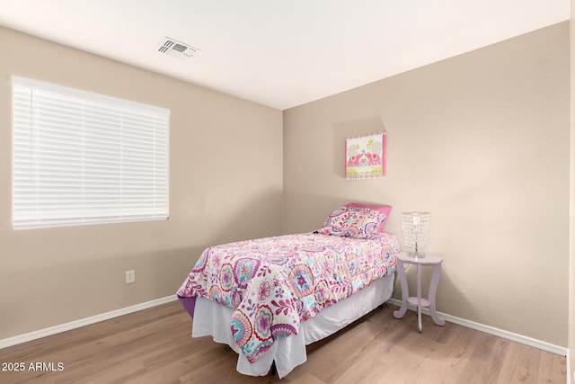 bedroom featuring wood finished floors, visible vents, and baseboards