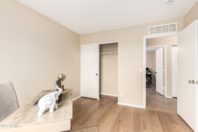 office area with visible vents, baseboards, and wood finished floors