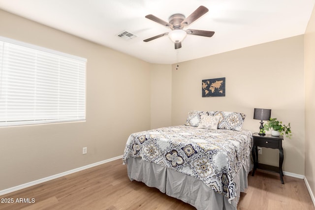 bedroom with a ceiling fan, wood finished floors, visible vents, and baseboards