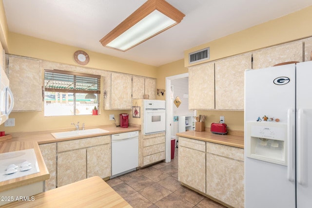 kitchen featuring sink, light tile patterned floors, and white appliances