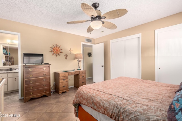 bedroom featuring light tile patterned floors, a closet, a textured ceiling, and ceiling fan