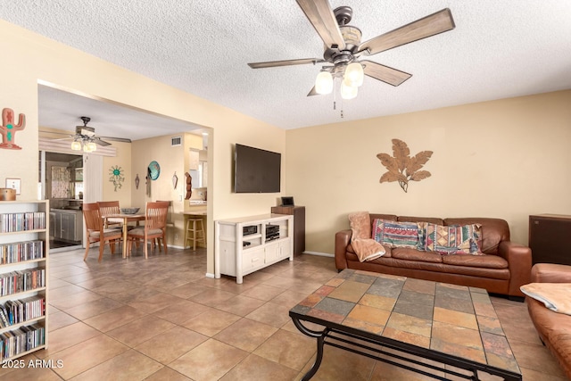 living room with ceiling fan, tile patterned floors, and a textured ceiling