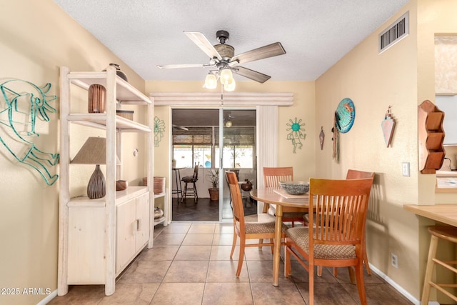 tiled dining space with ceiling fan and a textured ceiling