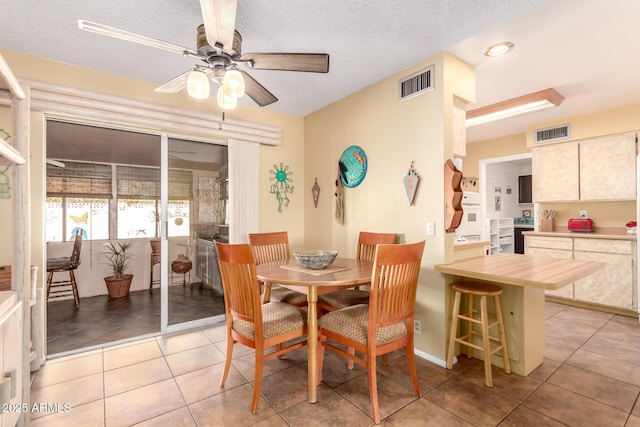 tiled dining room with ceiling fan and a textured ceiling