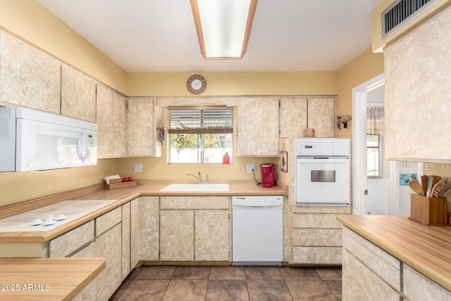 kitchen with dark tile patterned floors, sink, and white appliances